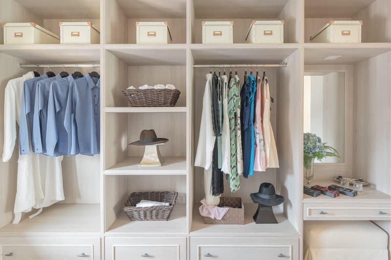 modern wooden wardrobe with clothes hanging on rail